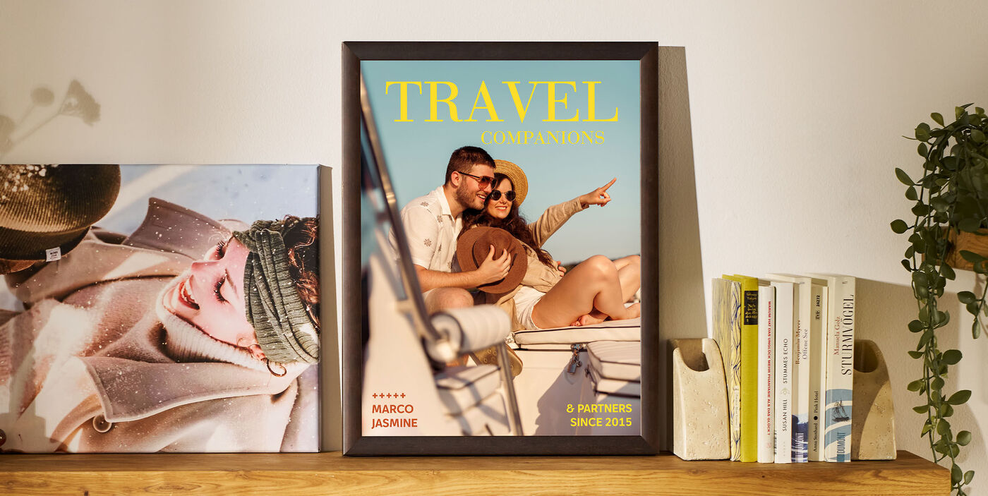 Egy bekeretezett poszter áll a polcon, könyvek és egy növény között. A poszteren egy hajón utazó pár látható, a felirat pedig: „TRAVEL companions”. Mellette egy téli ruhába öltözött nőről készült fotó áll.